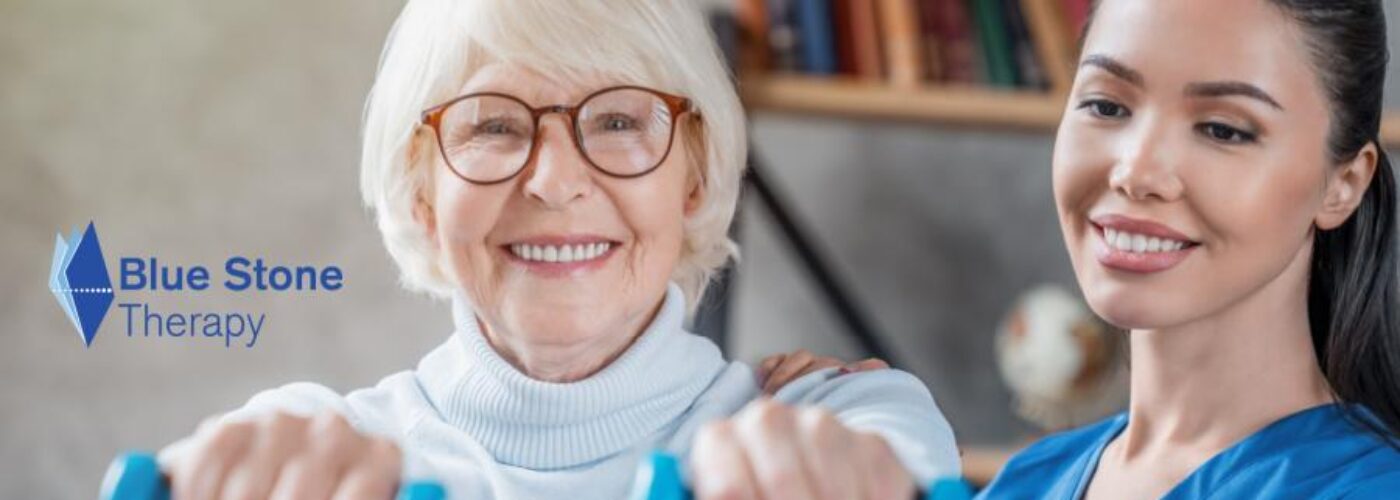 An elderly woman with short white hair and glasses smiles while holding blue dumbbells, supported by a young woman in a blue uniform. The logo Blue Stone Therapy is visible on the left side, highlighting their Care Initiative.