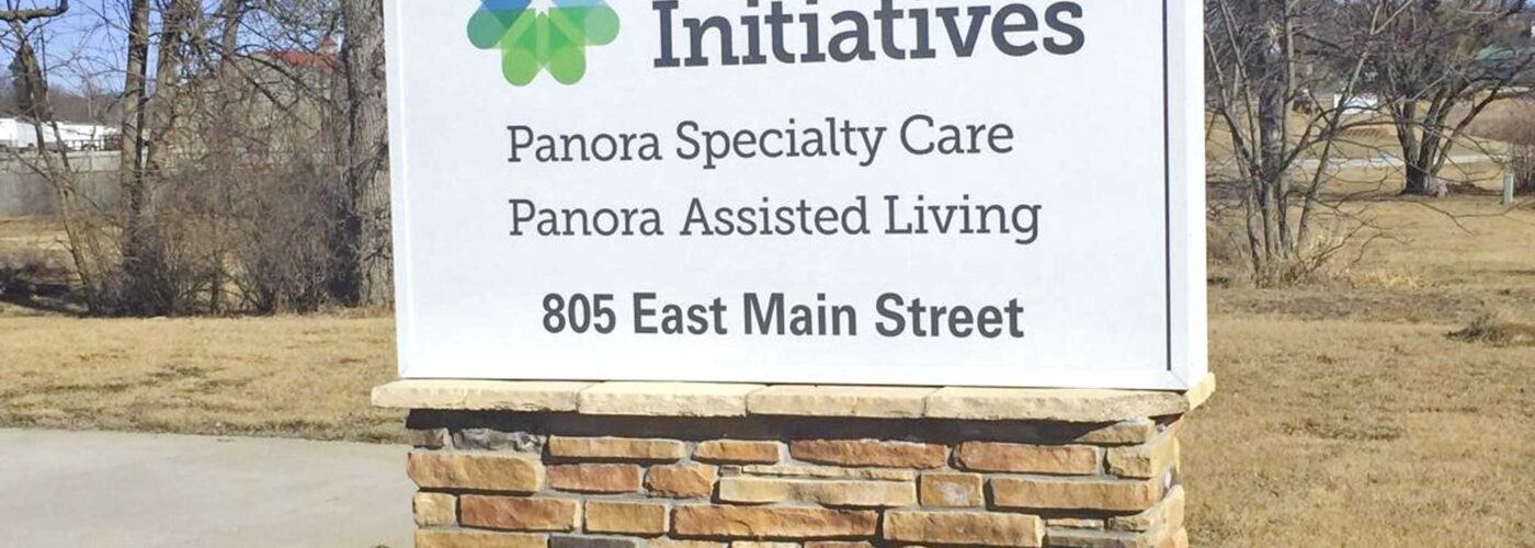 Sign for Care Initiative  
805 East Main Street  
Featuring Panora Specialty Care and Panora Assisted Living  

[Care Initiative Logo]  

The sign is mounted on a stone base, surrounded by greenery, with grass and trees in the background.